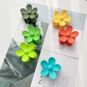 Close-up of matte flower hair clips in six assorted colors on a magazine background