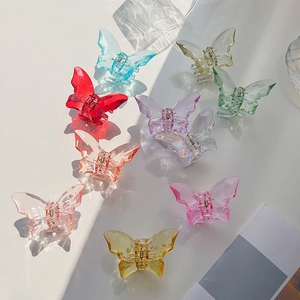Detailed flat lay of nine colorful transparent butterfly hair claws with shadows