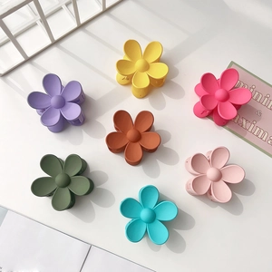 Detail view of seven matte flower-shaped hair claws in assorted pastel colors for women
