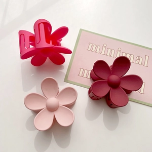 Detail view of matte flower hair claws in rose, pink, and dark red floral designs