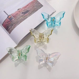 Detailed view of four colorful translucent butterfly hair claws on a clean desk