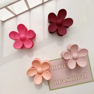 Detail view of four matte frosted flower hair claws in different shades of pink