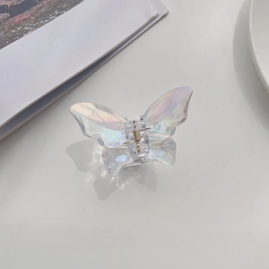 Iridescent butterfly hair claw clip with transparent finish on a minimalist desk