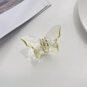 Detail of transparent butterfly hair claw with golden spring and faceted texture
