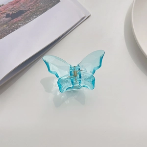 Detailed view of large transparent blue butterfly hair claw clip with bionic wings on white surface