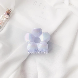Close-up of pearlescent flower hair claw clip with iridescent shine on silk fabric