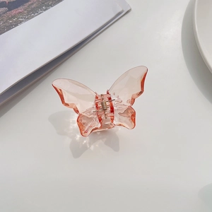 Detail view of large translucent pink butterfly hair claw clip with golden metal spring