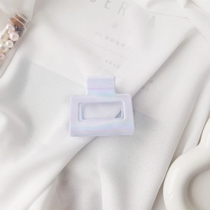 Detail of a square iridescent lavender hair claw clip on white silk background