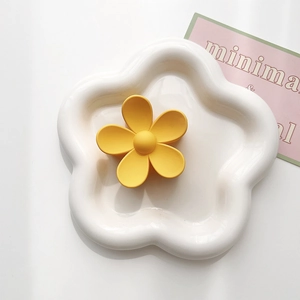 Macro detail of yellow matte flower hair claw clip on decorative white tray