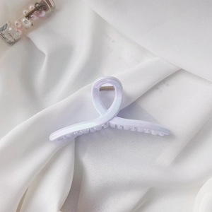 Detailed macro view of the iridescent purple hair claw clip with metallic spring on fabric