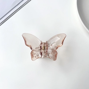 Detail of translucent mermaid-pink butterfly hair claw with golden metal spring