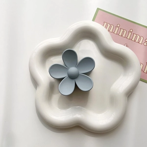 Detail of light blue matte flower hair claw clip displayed on a white ceramic plate