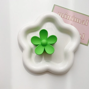 Close-up of matte green flower claw clip displayed on a white ceramic floral tray