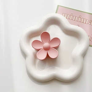Detailed view of pink matte flower hair claw clip on white ceramic display tray