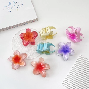 Macro detail of various gradient plumeria flower hair claws with glossy resin texture