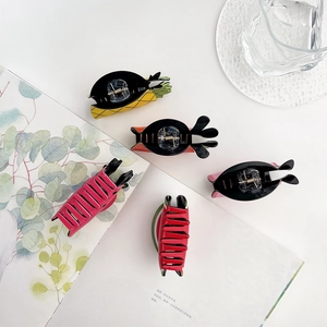 Detailed view of colorful fruit-themed acrylic hair claws in pineapple and watermelon designs