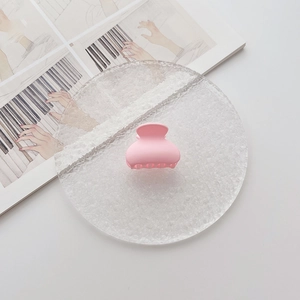 Nahaufnahme einer kleinen rosa mattierten Haarklammer auf einem eleganten Glasteller