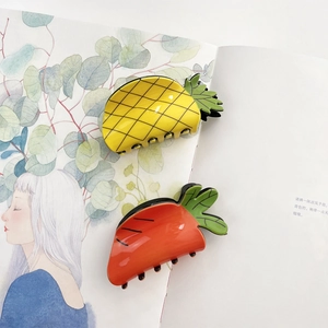 Cute acrylic fruit claw clips featuring pineapple and carrot designs on magazine background
