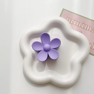 Macro detail of lavender matte floral hair claw clip on white ceramic flower plate