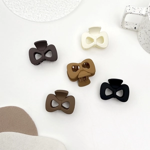 Five matte butterfly hair claws in earth tones shown on a minimalist white tray background