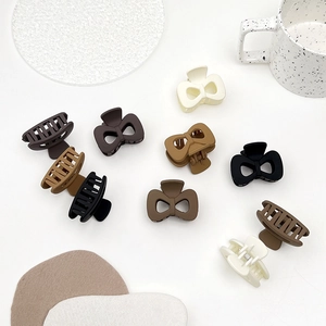 Detailed view of matte bow hair claws in various earth tones on a minimalist background