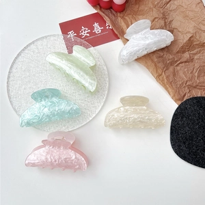 Detail of marble pattern acrylic hair claws in five soft colors on a glass tray