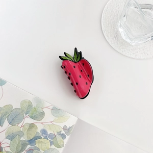 Close-up of cute strawberry-shaped hair claw clip with pink acrylic and green leaf detail