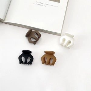 Detailed set of four matte hair clips in brown, cream, black and khaki on a book