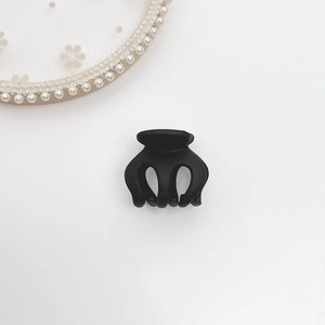 Detailed close-up of a matte black mini hair claw clip with multi-tooth design on a lace tray