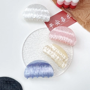 Detail view showing four acrylic hair claws with marble textures and pearlescent finish