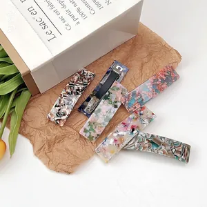 Detail view of rectangular acetate hair clips with floral and tortoiseshell patterns
