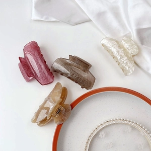 Elegant marble acetate hair claws in four colors shown on a luxury decorative plate