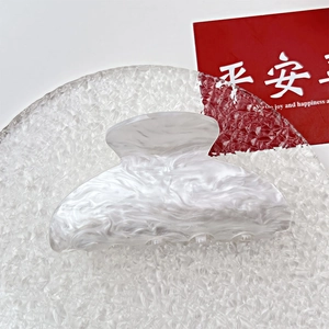Close-up of marble pattern acrylic hair claw clip on decorative ice textured plate