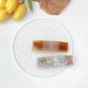 Close-up of elegant acetate hair clips in amber brown and colorful mosaic patterns