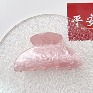 Detailed close-up of pink marble acrylic hair claw clip with glossy finish and secure teeth