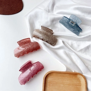Detail showing four acetate hair claws with fibrous textures on white silk background