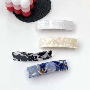 Detailed macro view of four marble pattern acetate hair clips on a clean white surface