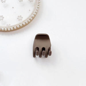 Close-up of a matte dark brown small hair claw clip on a decorative pearl lace tray
