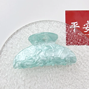 Detail view of large mint blue acrylic hair claw with elegant marble water ripple texture