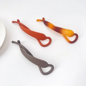 Détail de pinces bananes torsadées en résine mate aux couleurs rouge, ambre et gris-brun