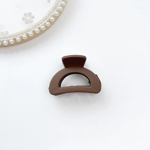 Detailed top view of a dark coffee matte hair claw clip on white lace background