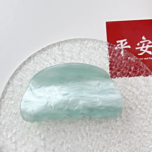 Close-up of a light green marble pattern acrylic hair claw clip with an elegant crescent design