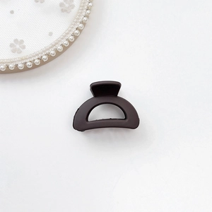 Close-up of matte dark brown hair claw clip on white lace and pearl background