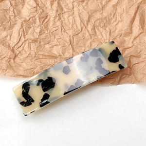Detailed texture of an elegant rectangular tortoise shell hair clip in cream and black finish
