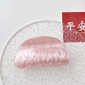 Macro detail of pink pearlescent acrylic hair claw with marble texture and round design