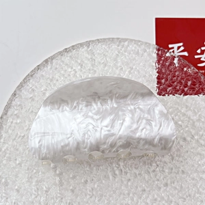 Detail view of pearl white acrylic hair claw with elegant marble texture and glossy finish