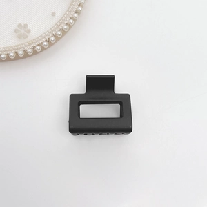 Close-up of matte black square hair claw clip with a minimalist hollow design on white