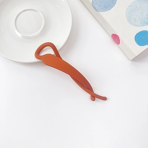 Détail d'une pince banane orange mat avec une texture antidérapante et design épuré