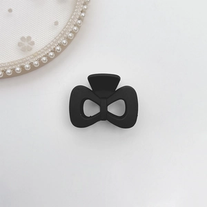 Macro shot of a matte black bow-shaped hair claw clip on elegant white lace background