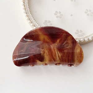 Macro detail of amber marble acetate hair claw clip with golden glitter finish